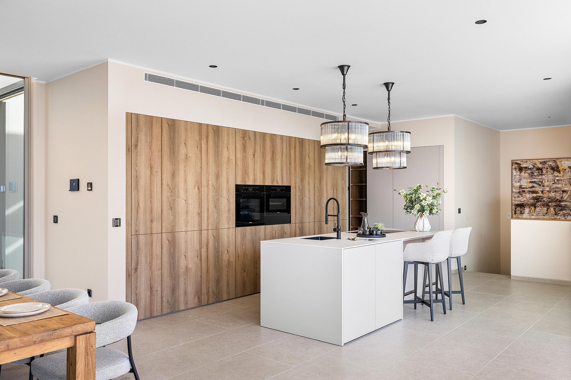 Fitted kitchen with full-height oak cabinetry, white composite island and two black-frame pendant lights