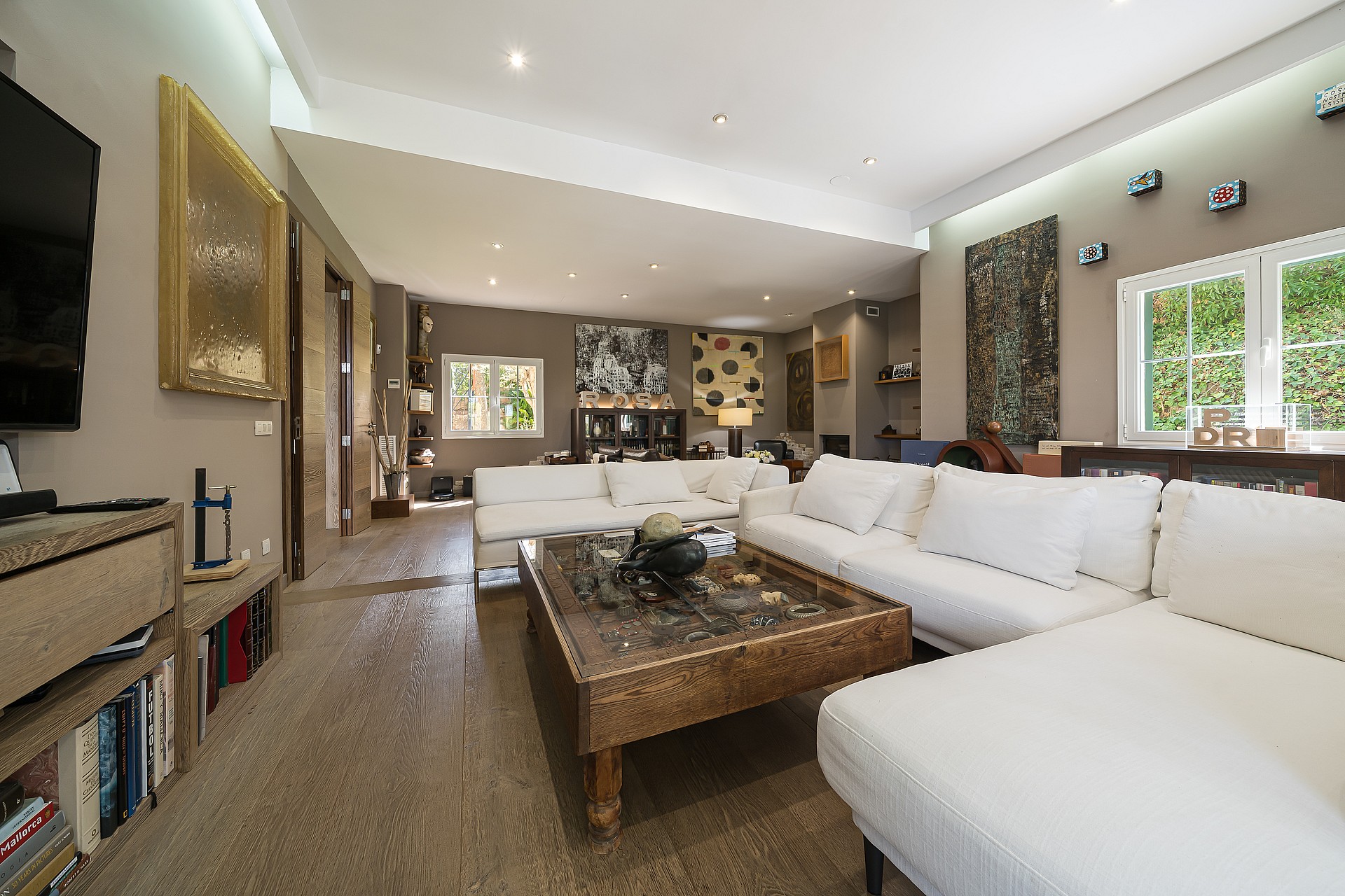 Spacious living room featuring white modular sofas, a stone-topped coffee table, and beige tiled floors under recessed lighting.