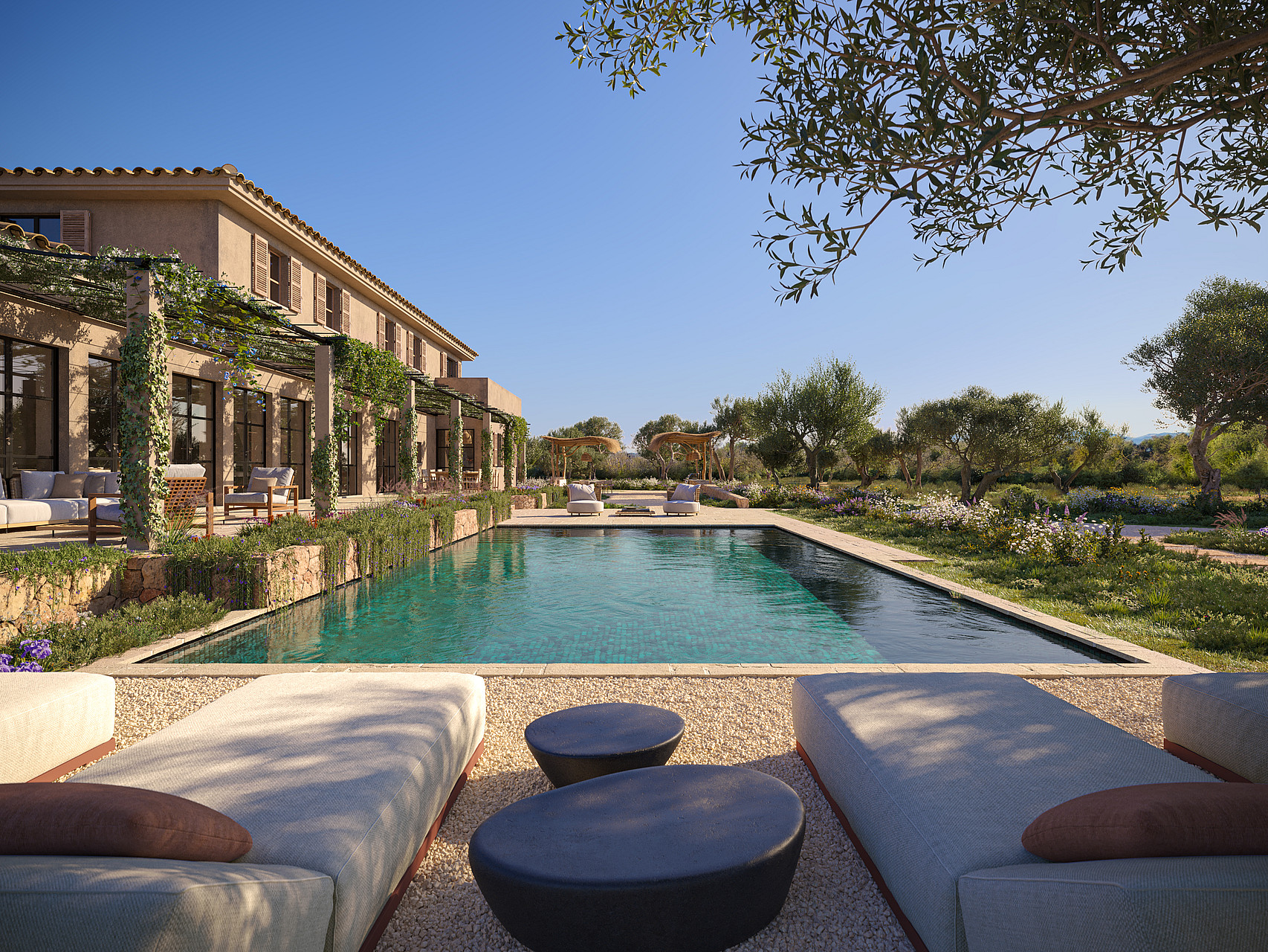 A wide exterior view of a finca with a rectangular swimming pool, gravel patio, sun loungers, and pergola overlooking mountains.