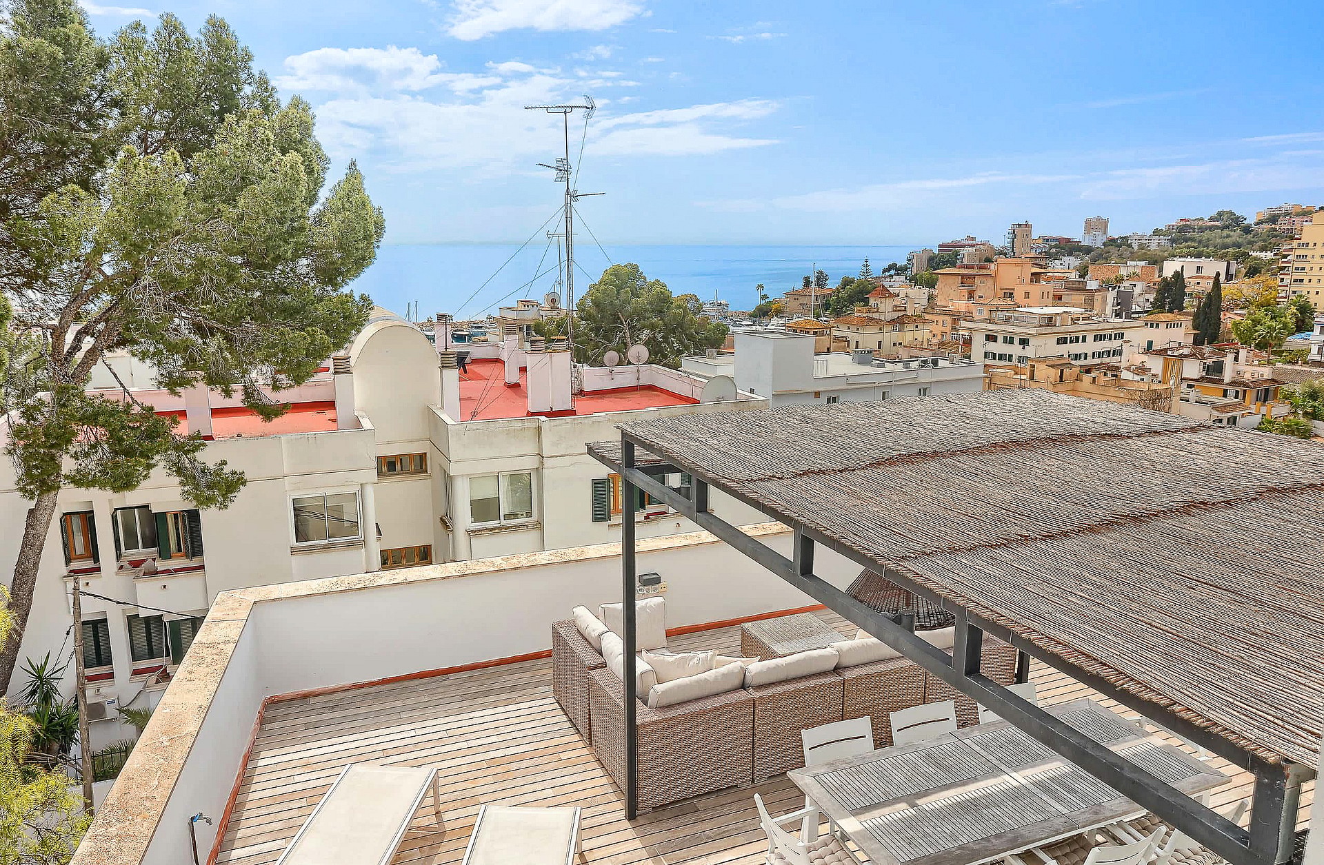 High-angle view of an outdoor terrace with a pergola, lounge seating, and dining area overlooking the San Agustin coastline.