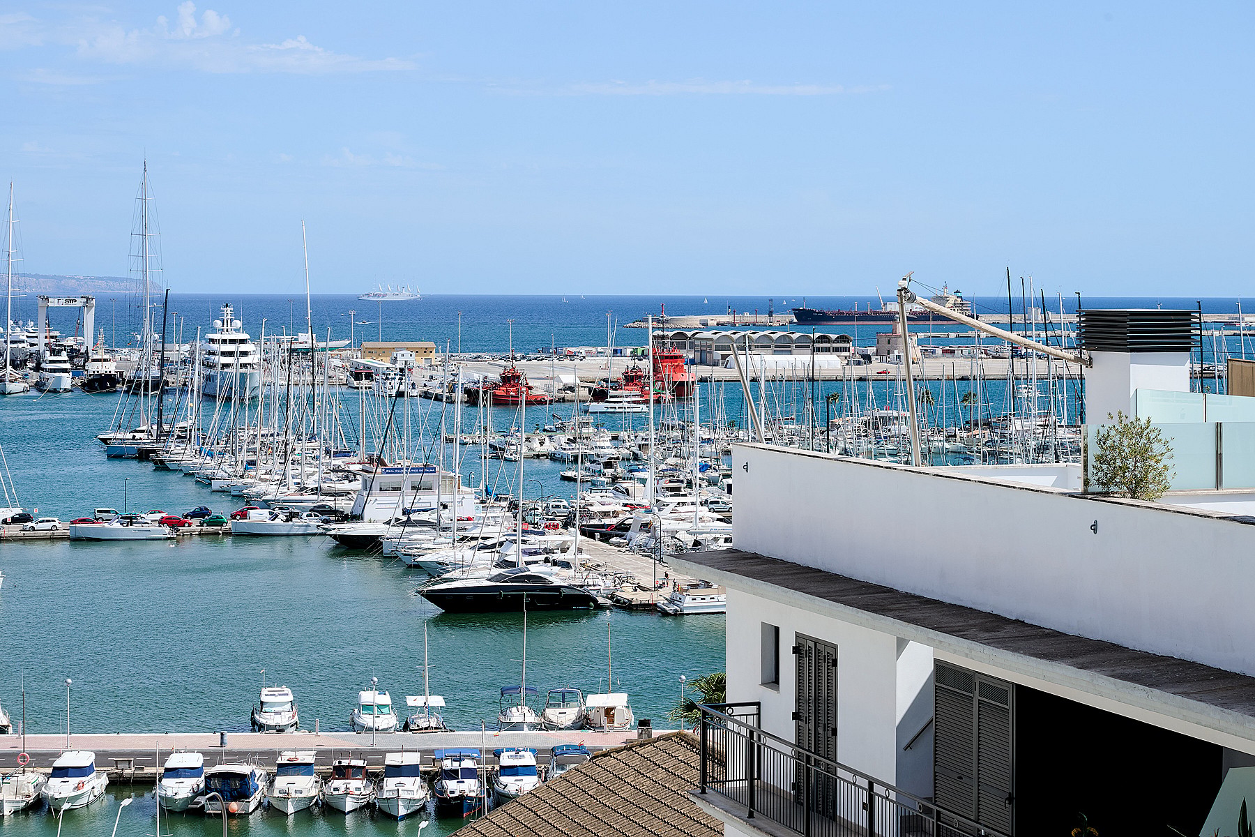 Elevated view overlooking a marina filled with yachts and boats under a bright blue sky.