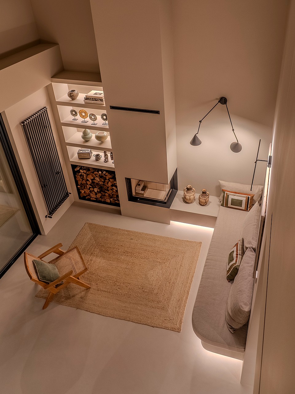 High-angle view of a minimalist seating area featuring a corner fireplace, low-profile bench, and illuminated display shelves.