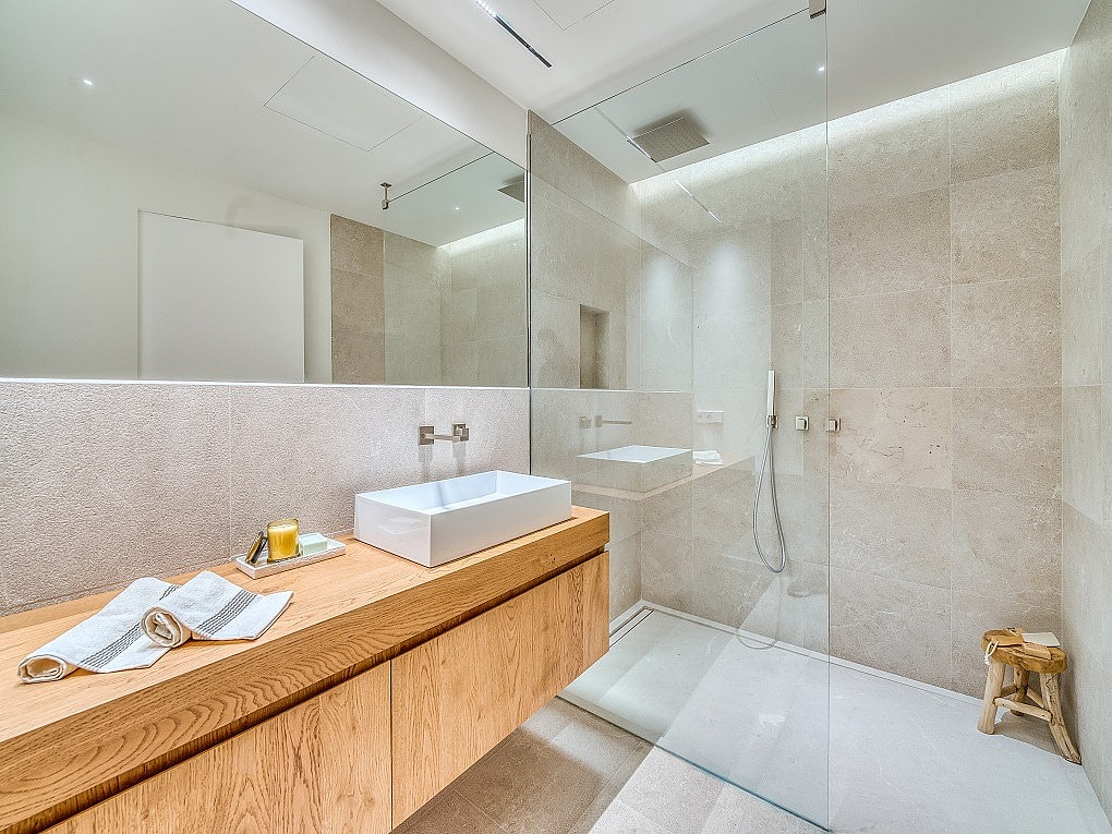 Contemporary bathroom featuring a floating light oak vanity, white vessel sink, large mirror, and walk-in glass shower.