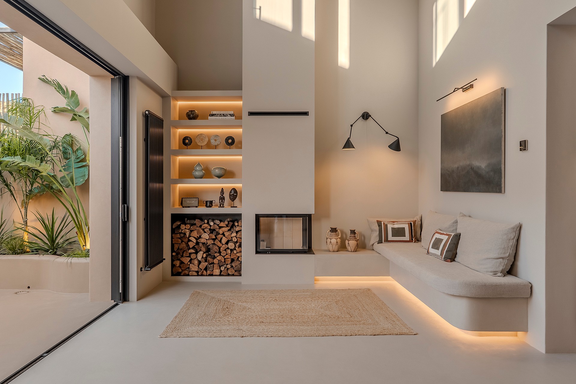 Living room featuring a recessed fireplace, built-in banquette seating, and sliding glass doors to a leafy courtyard.