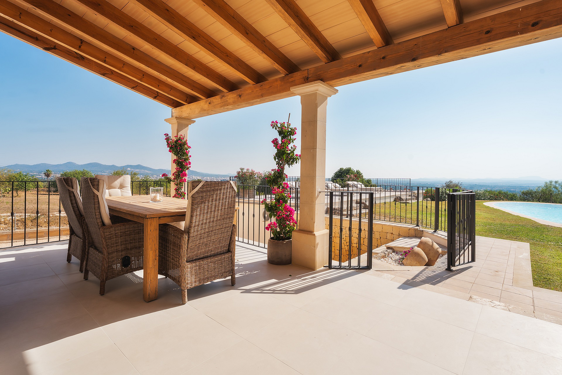 Comedor exterior en terraza con muebles de mimbre, vigas de madera y vistas al paisaje de montaña.
