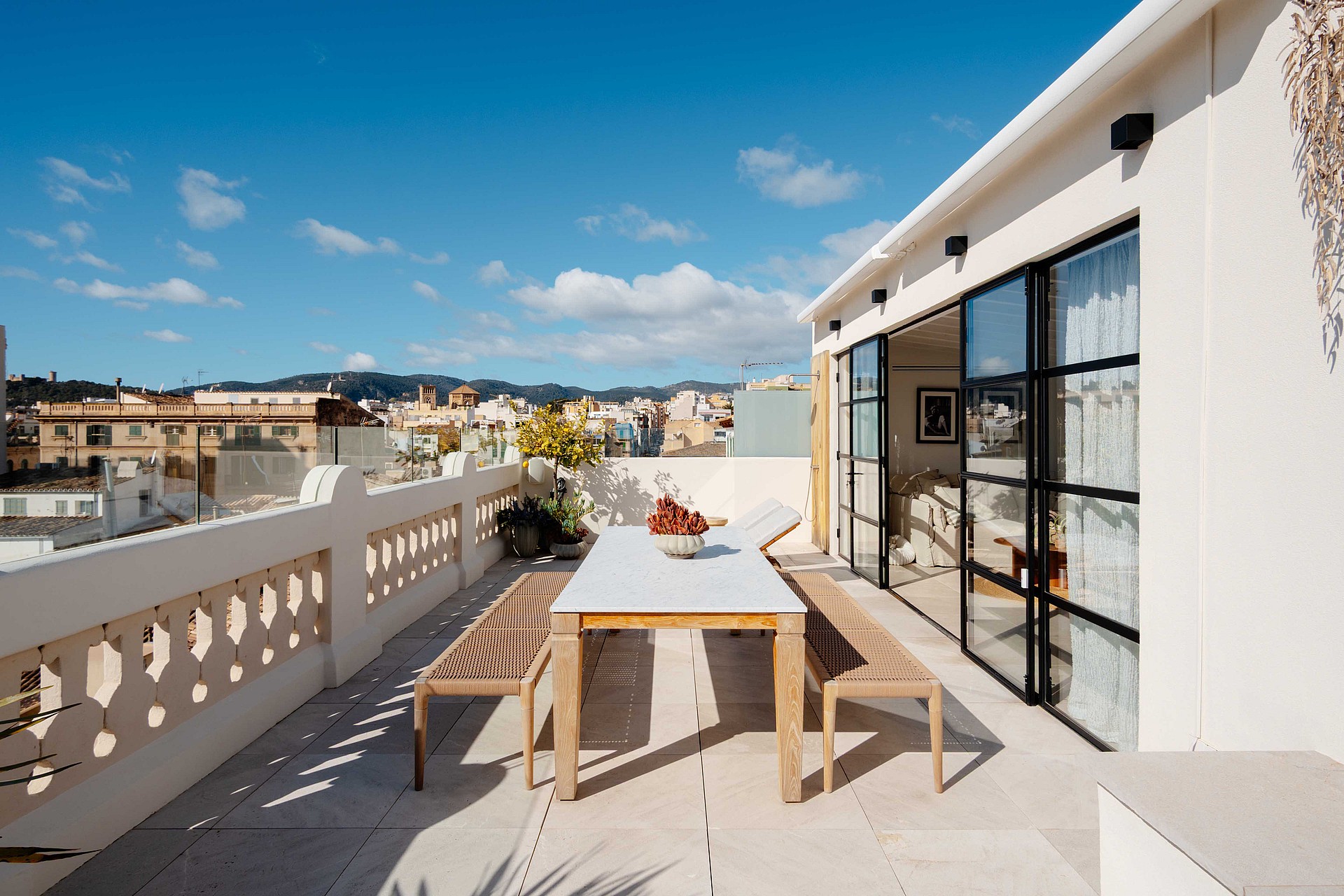A rooftop terrace with a dining table and benches overlooking the Santa Catalina district under a clear blue sky.