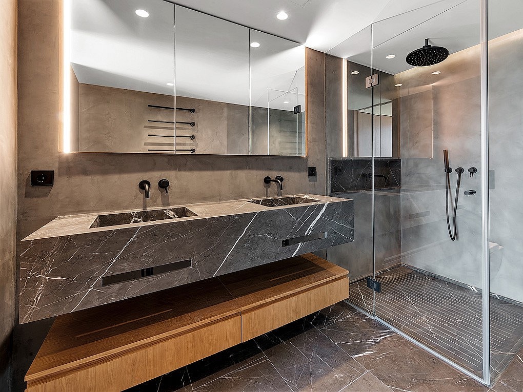 Modern bathroom featuring a floating grey marble double vanity with matte black fixtures, integrated LED mirror lighting, and a glass-enclosed rain shower.
