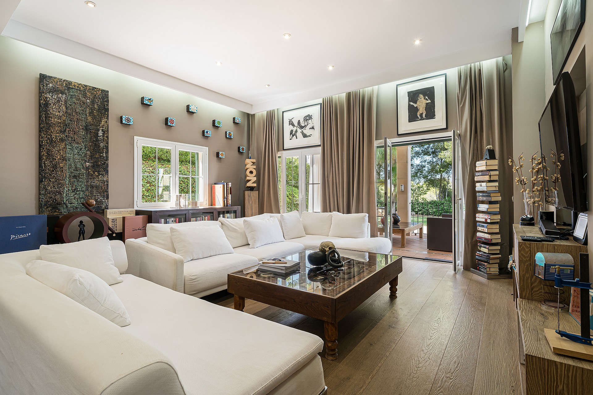 Spacious living room featuring white modular sofas, a central dark wood coffee table, and floor-to-ceiling curtains.
