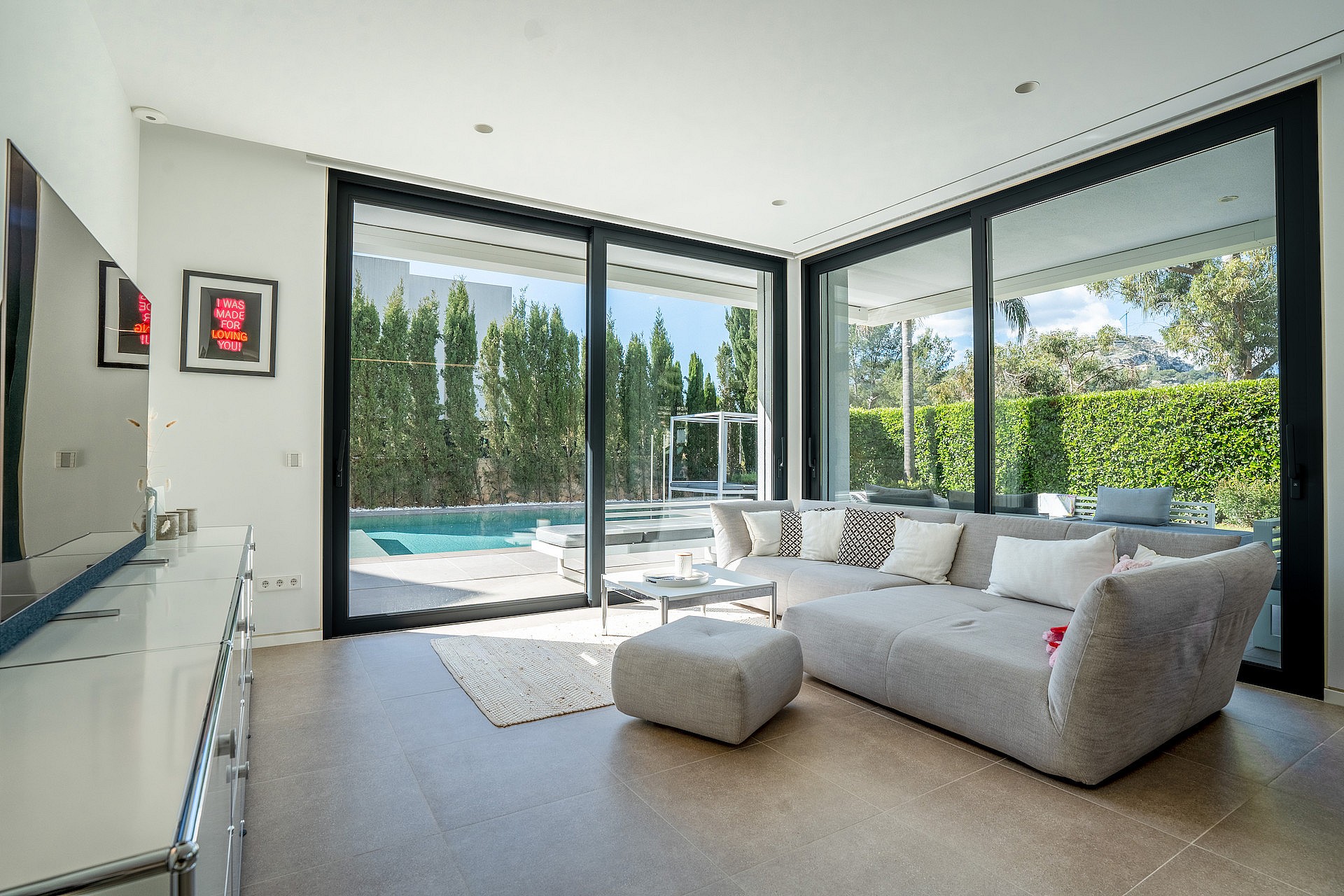 Living area with grey sectional sofa and sliding glass doors opening onto the swimming pool.