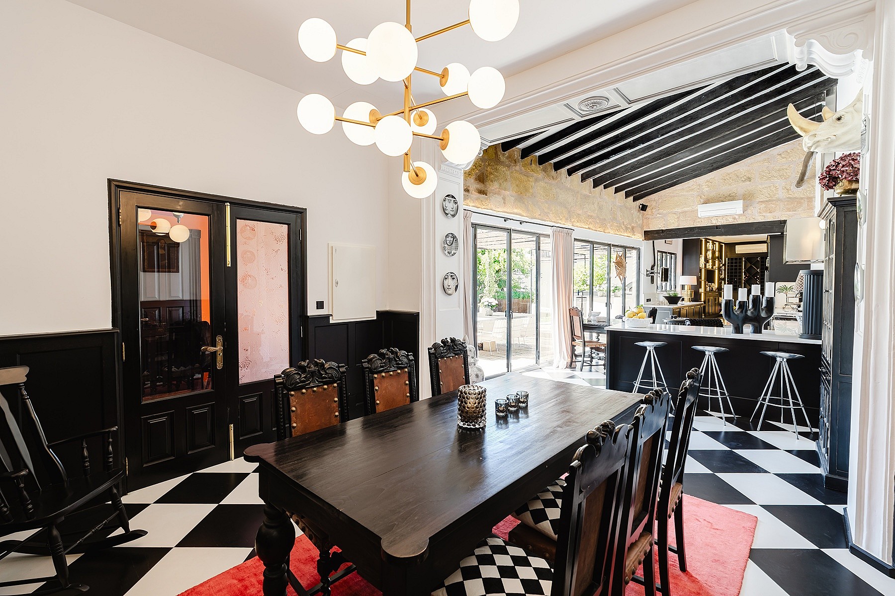 Dining area featuring black and white checkerboard tile flooring, a dark wood dining table, and a modern globe chandelier.