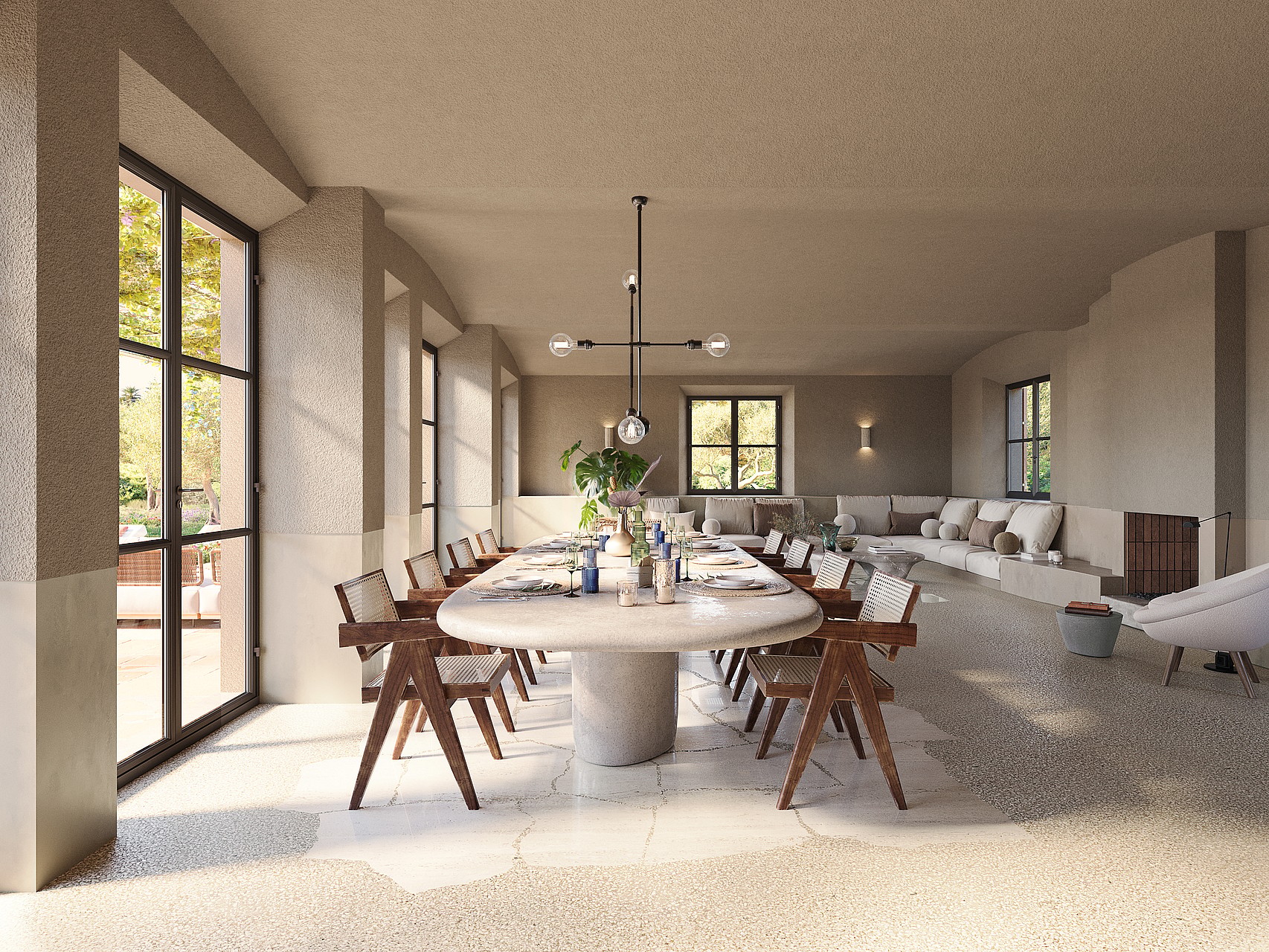 Dining room with a large oval stone table and wooden chairs, set against stone walls and large black-framed glass doors.