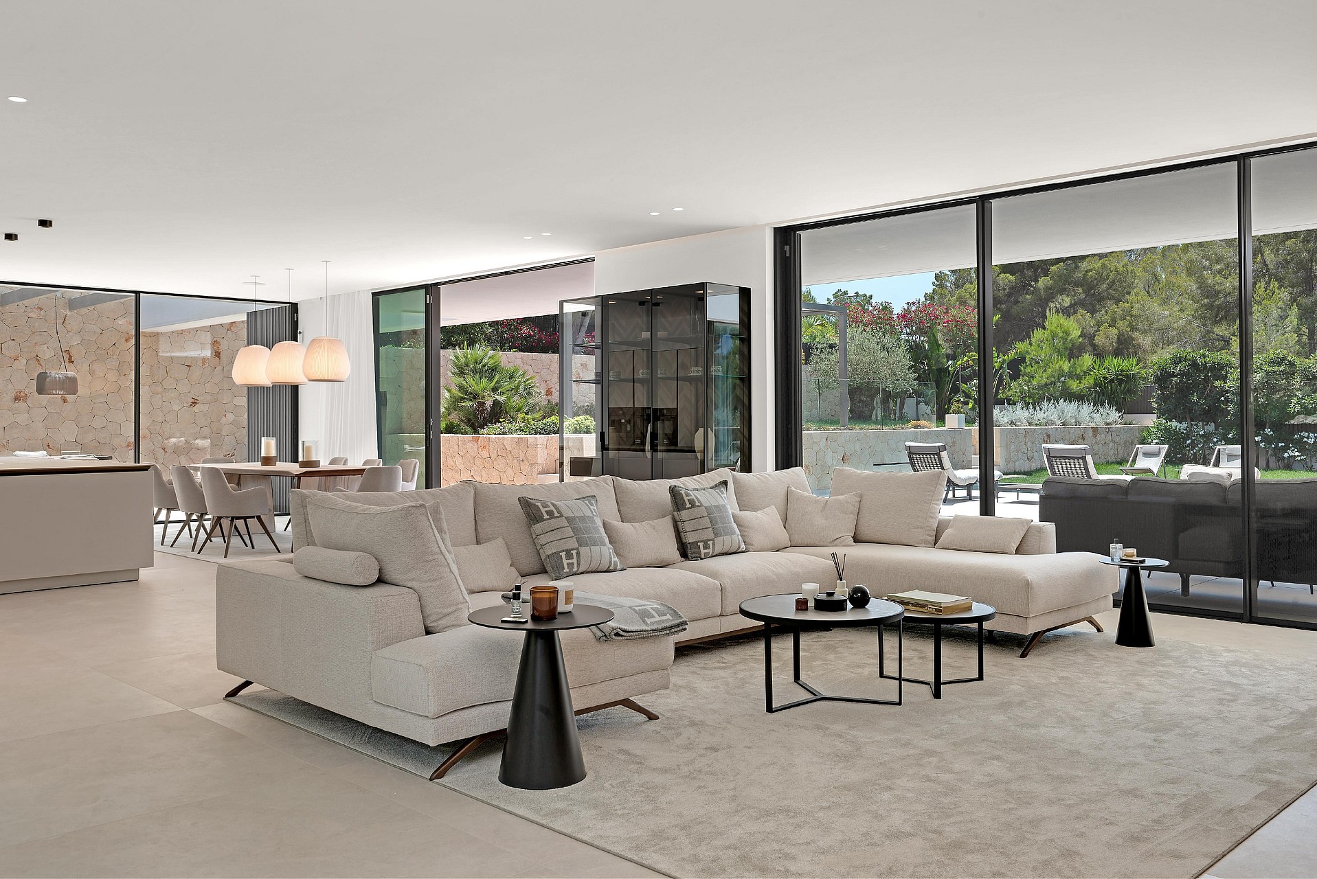Open-plan living room with large sectional sofa, dining table and floor-to-ceiling glazing to garden