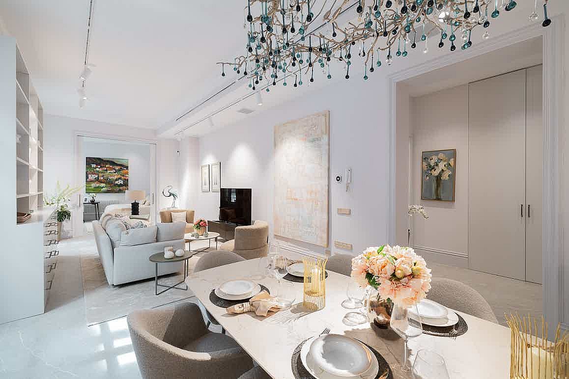 Bright open-plan living area featuring a modern dining set with upholstered chairs and a sofa area with neutral textiles.