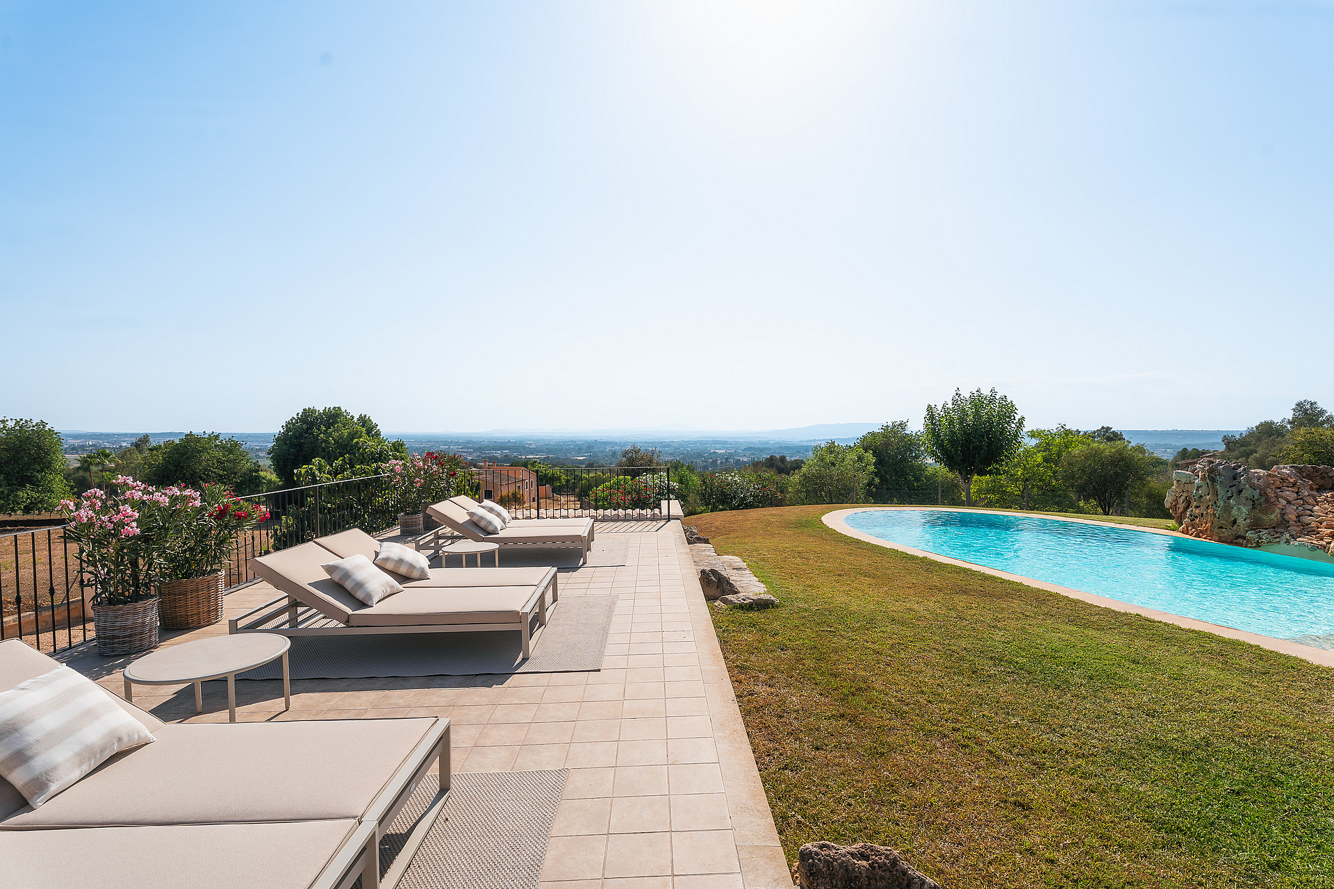 Terraza de piscina en Manacor con tumbonas sobre pavimento hacia el paisaje montañoso lejano.
