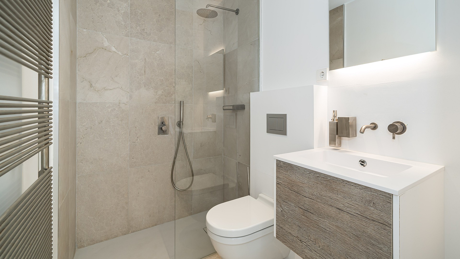 Modern bathroom featuring a wall-mounted floating vanity with wood-grain finish, white countertop, glass walk-in shower, and concealed toilet flush plate.