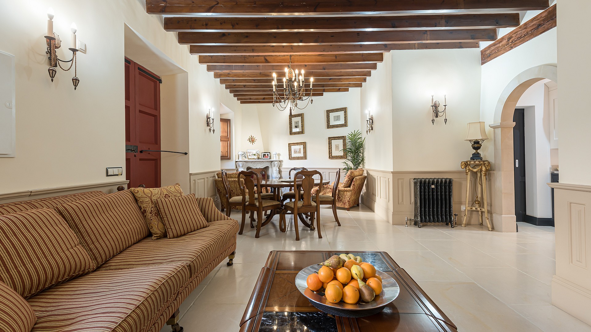 Living and dining area with striped sofa, wooden dining table and beamed ceiling