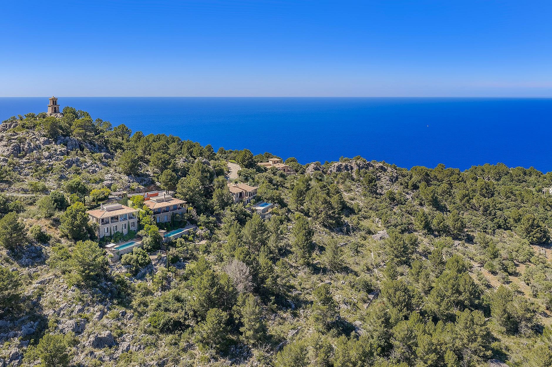 Aerial view of George Sand Villa nestled in the pine-covered hills of Valldemossa overlooking the Mediterranean Sea.