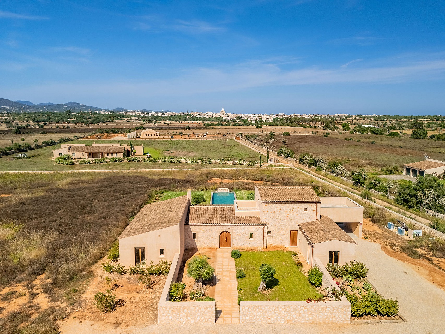 Aerial view of a traditional stone finca with tiled roofs, a private swimming pool, and landscaped gardens in a rural setting.
