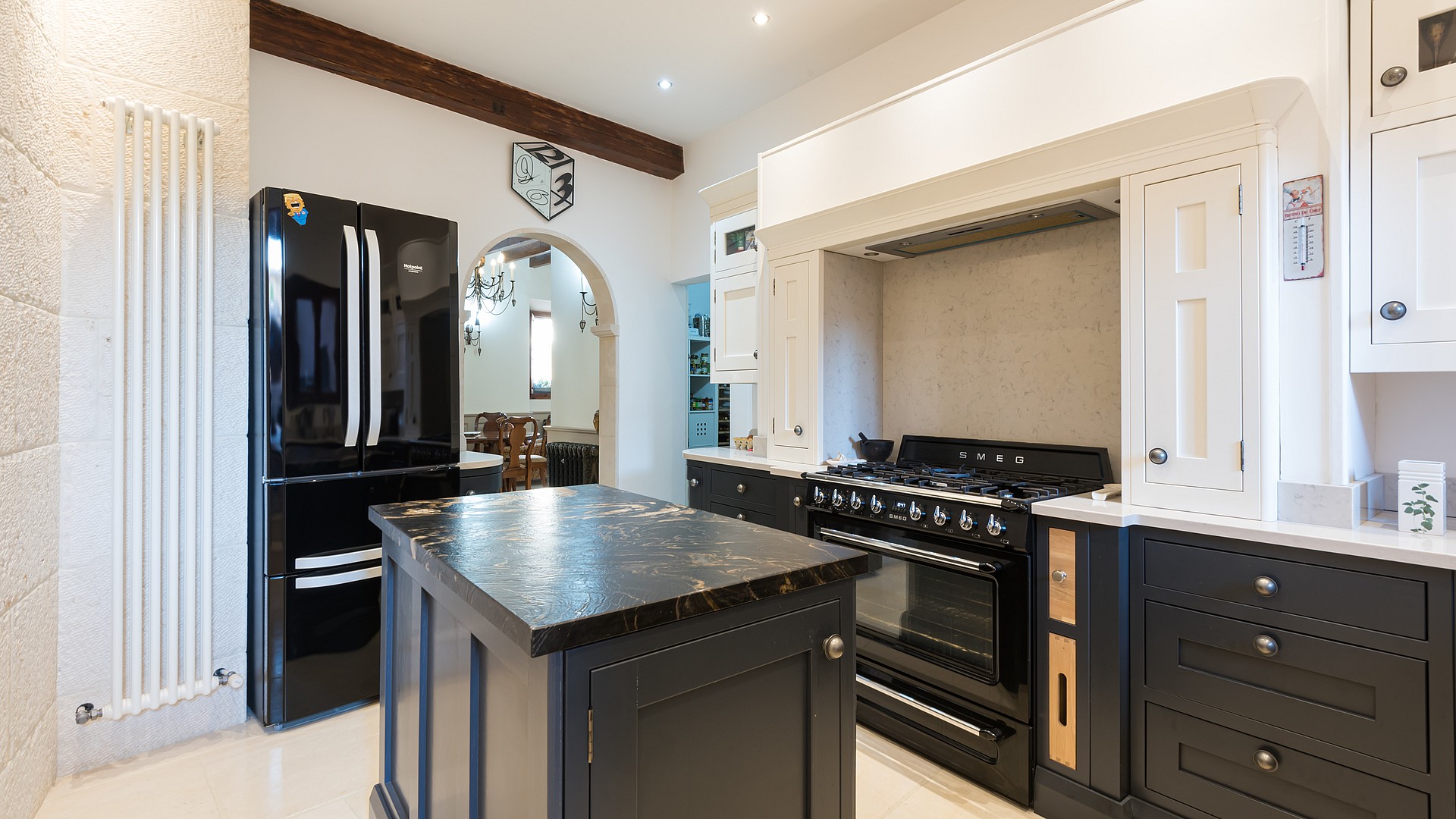 Kitchen with black cabinetry, marble-topped island and black SMEG range cooker