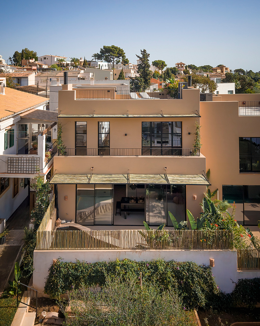 Exterior view of a multi-story townhouse in Genova with a sand-colored render, flat roof, and metal-framed windows.