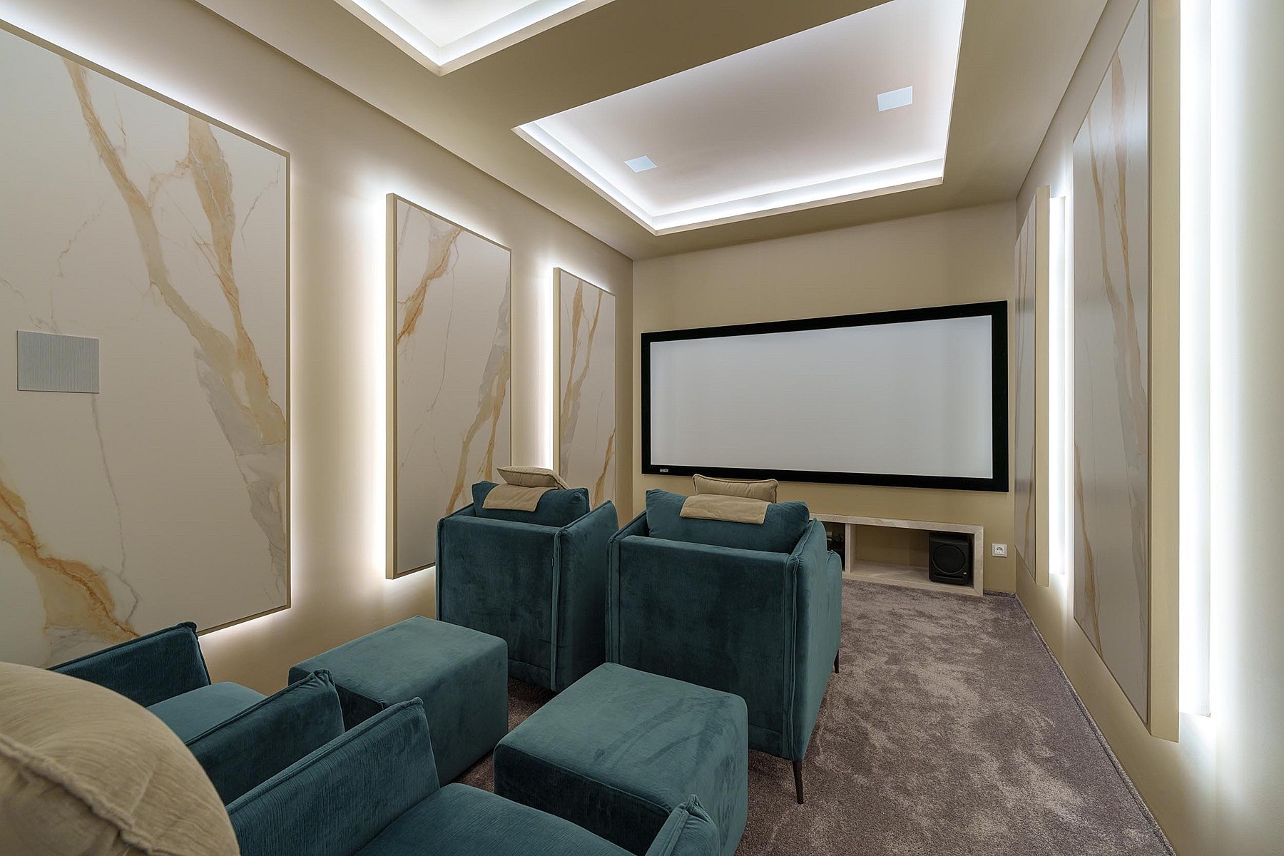 A private home cinema room with teal upholstered armchairs, large projection screen, and integrated LED lighting on walls.