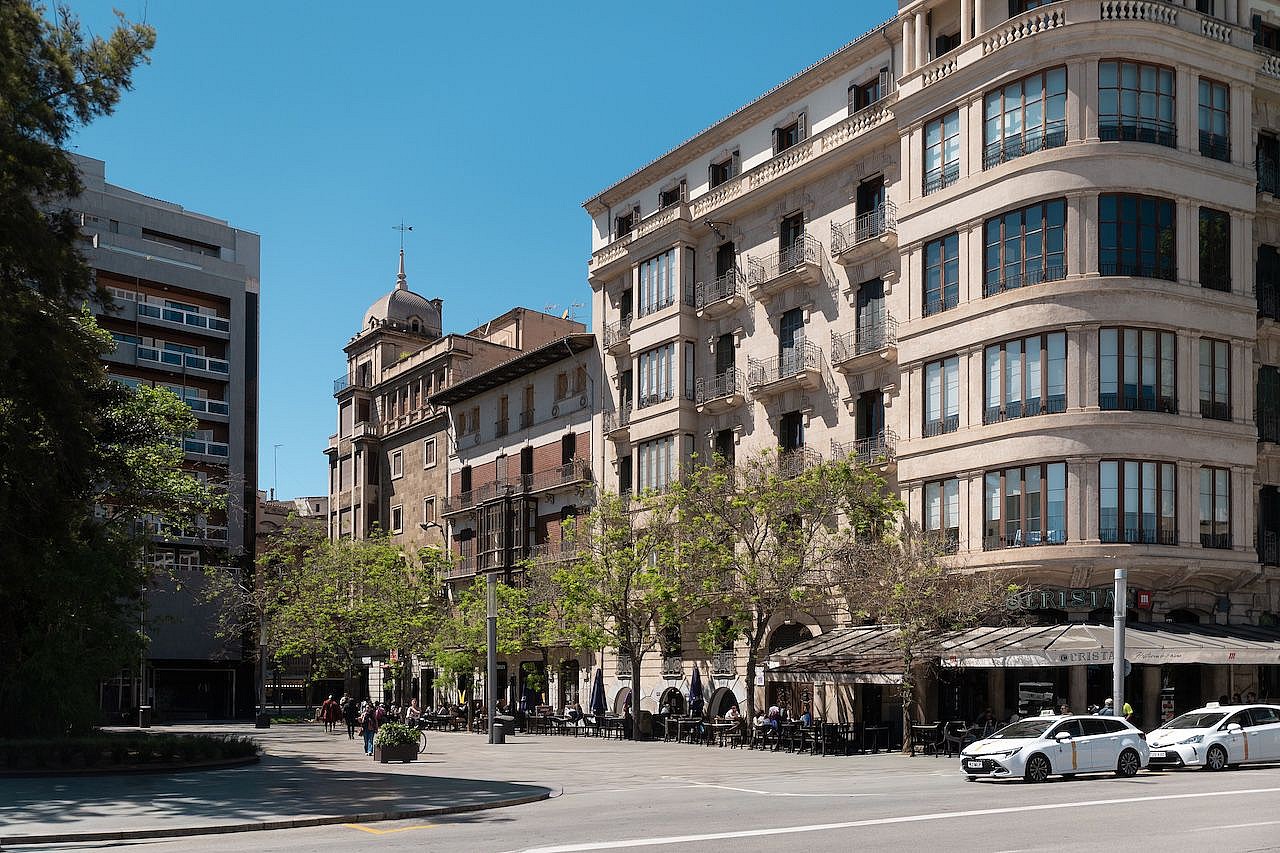 Street-level view of a classic beige residential building on a corner in Palma with multiple windows and balconies.