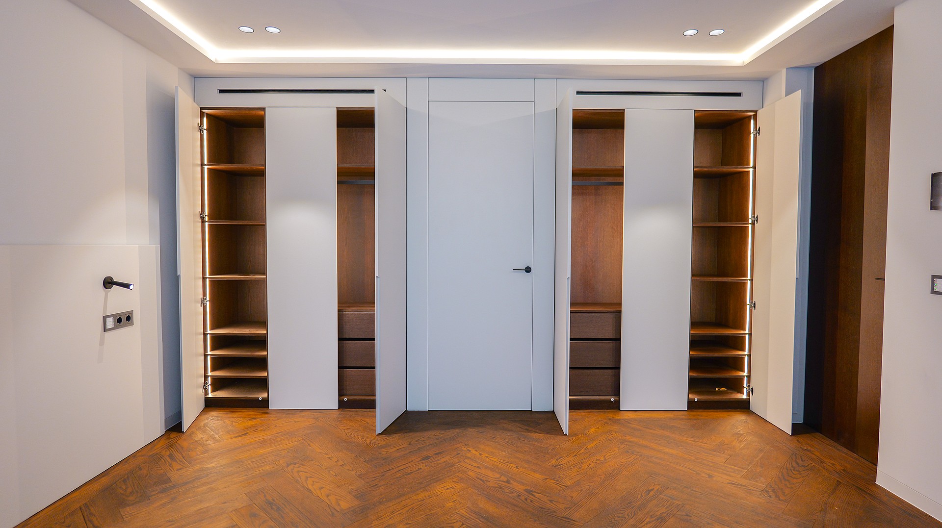 A floor-to-ceiling built-in wardrobe with white doors and wooden interior shelving, featuring integrated LED accent lighting.