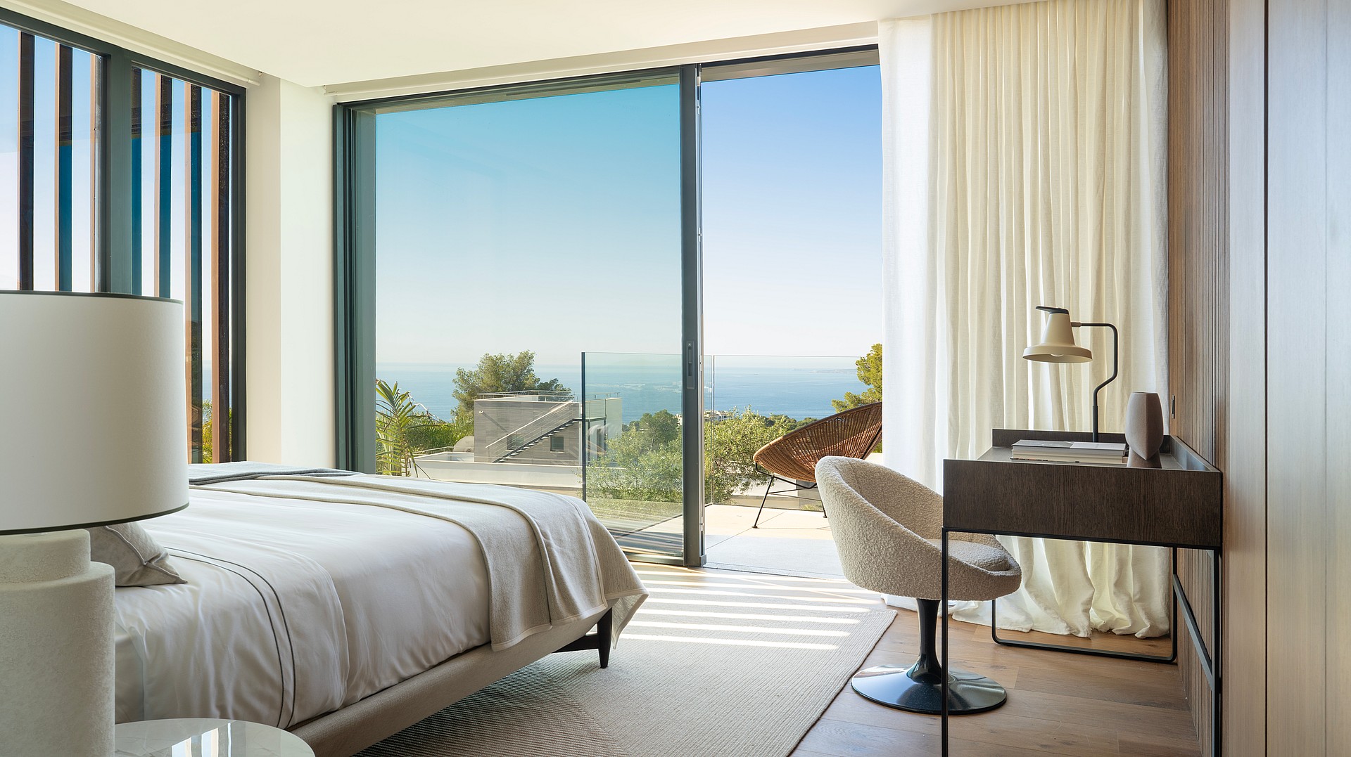 Master bedroom featuring a double bed, modern desk, and floor-to-ceiling windows overlooking the sea.