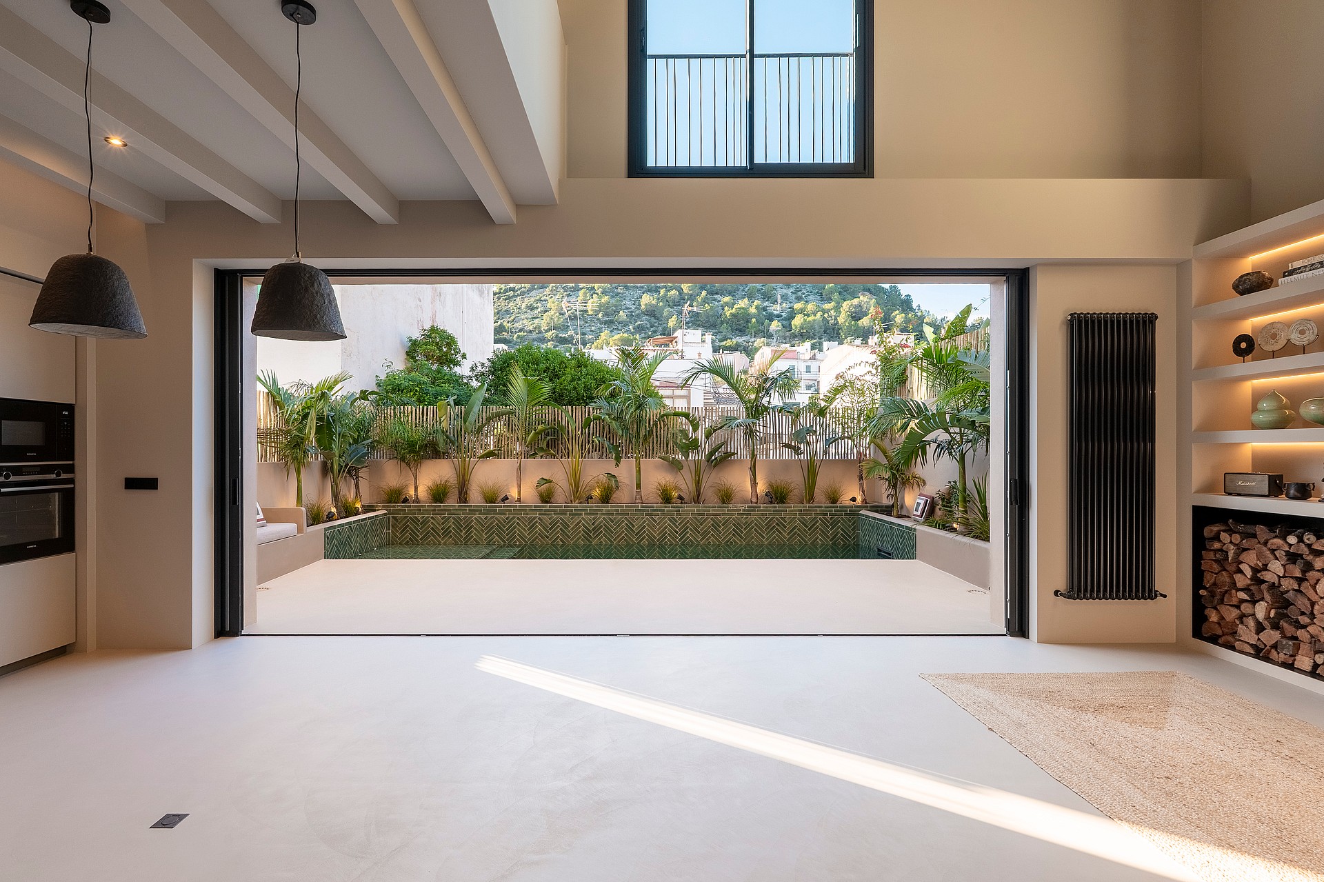 Open-plan living space featuring full-width sliding doors that lead to a private terrace with a pool and mountain views.