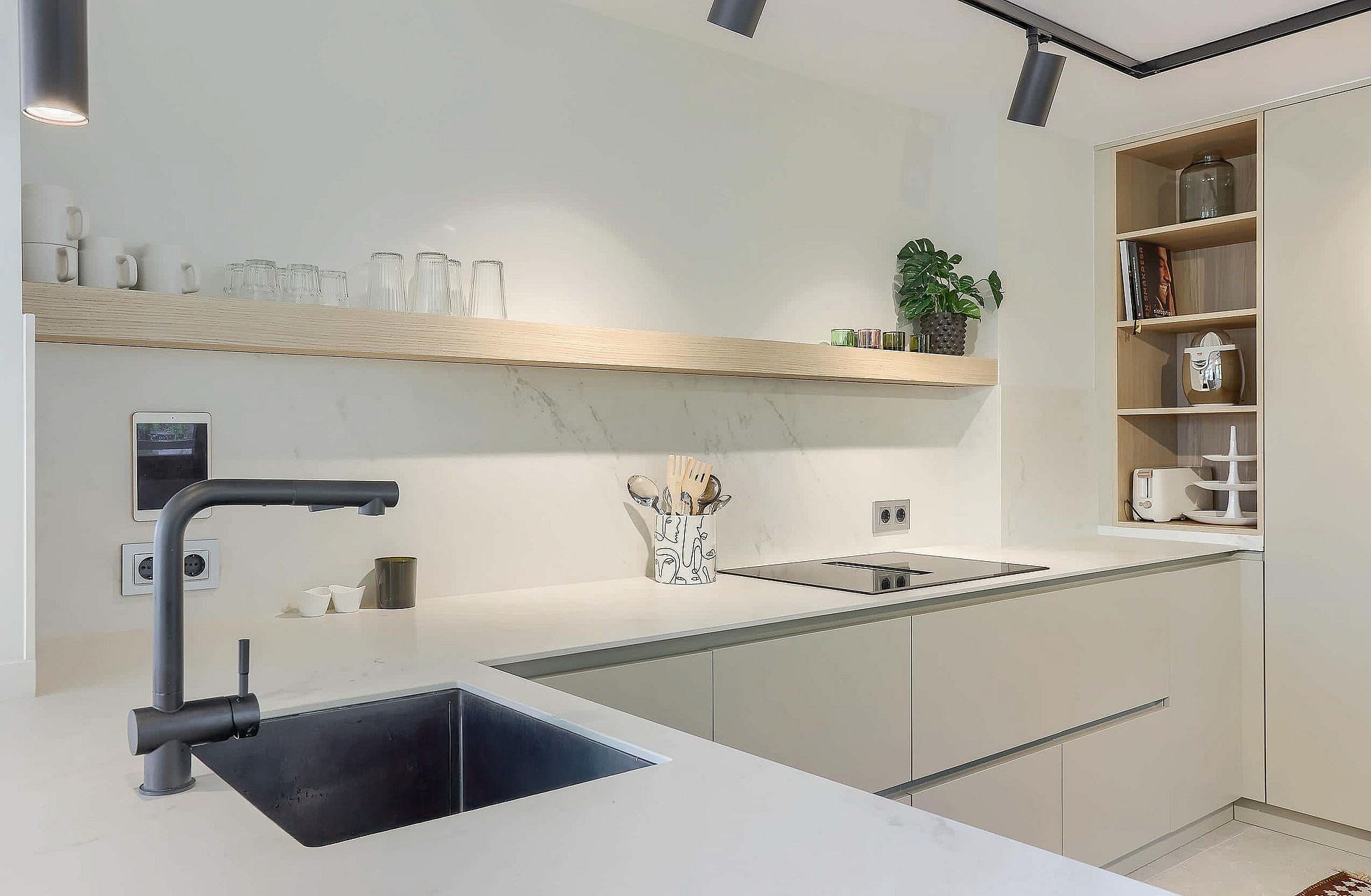 Modern kitchen featuring matte white cabinets, light wood shelving, and a dark faucet above a stainless steel sink.
