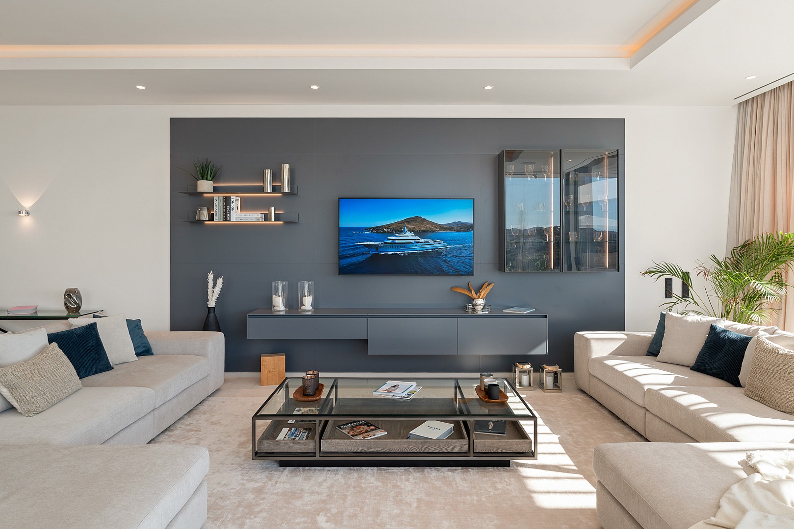 Symmetrical living area featuring a central charcoal media wall, floating grey console, and two beige sofas facing each other.