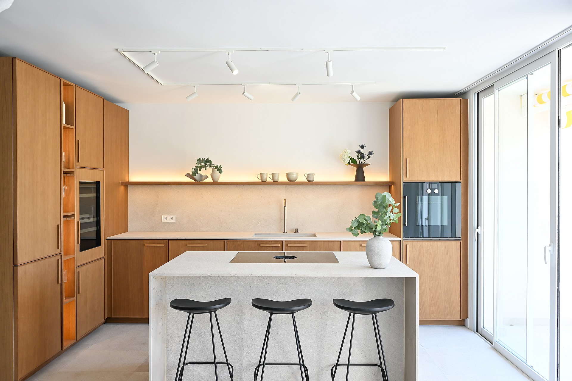 Open-plan kitchen in oak and Binissalem marble with sculptural concrete staircase and Zarci stone floors