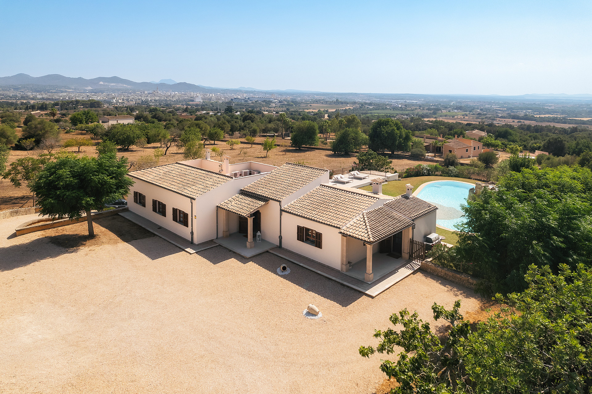 Vista aérea de una finca tradicional en Manacor con tejado de teja, jardín y piscina frente a la montaña.