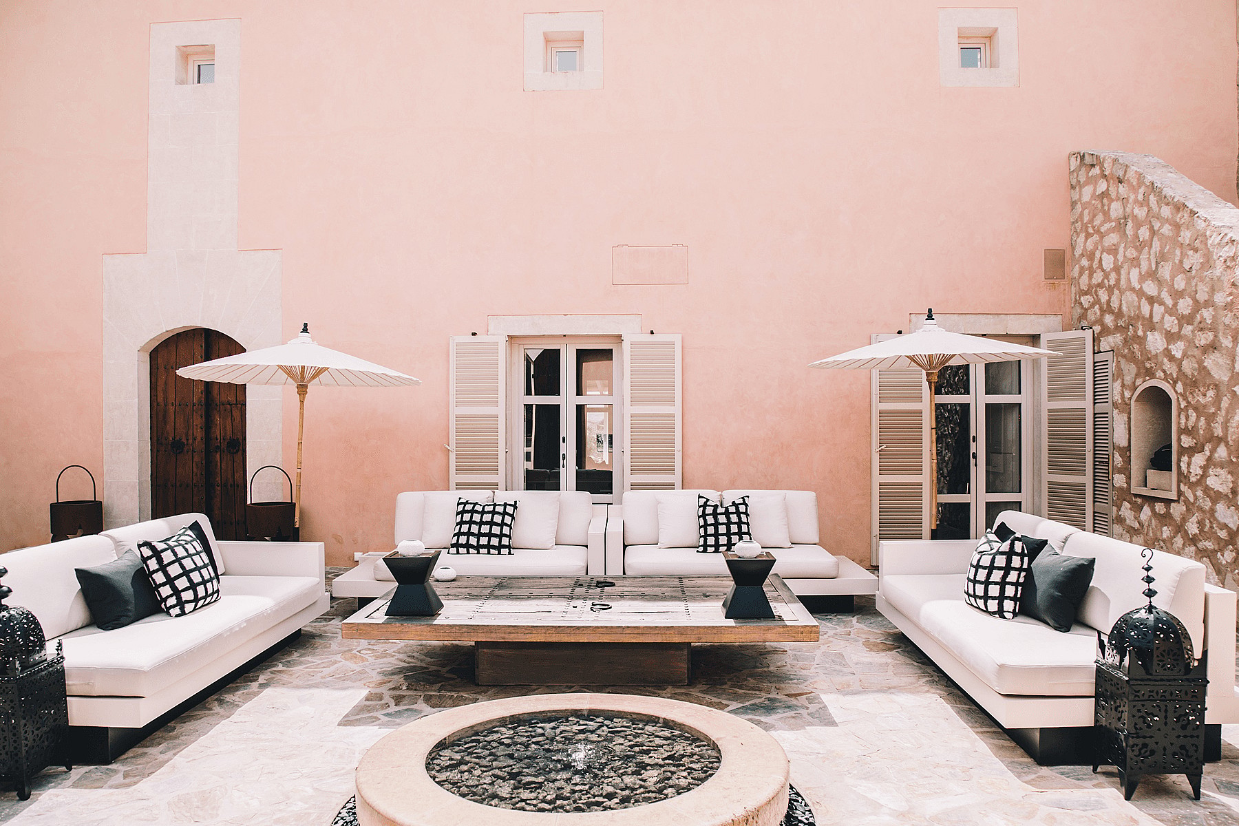 Outdoor courtyard of a Finca with pink plaster walls, white sofas, and stone flooring.