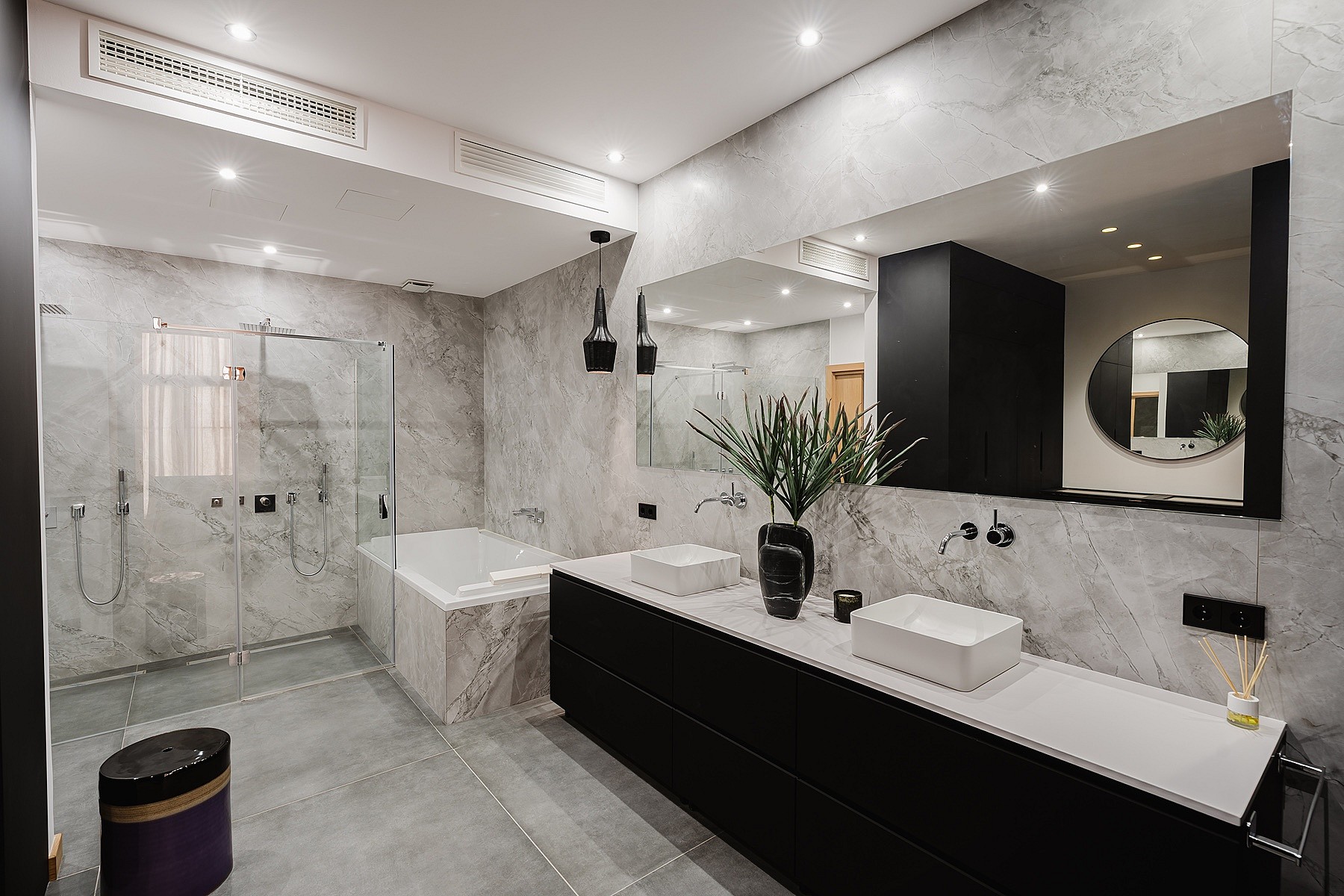Modern bathroom featuring gray marble walls, a black floating vanity with double sinks, and a glass-enclosed walk-in shower.