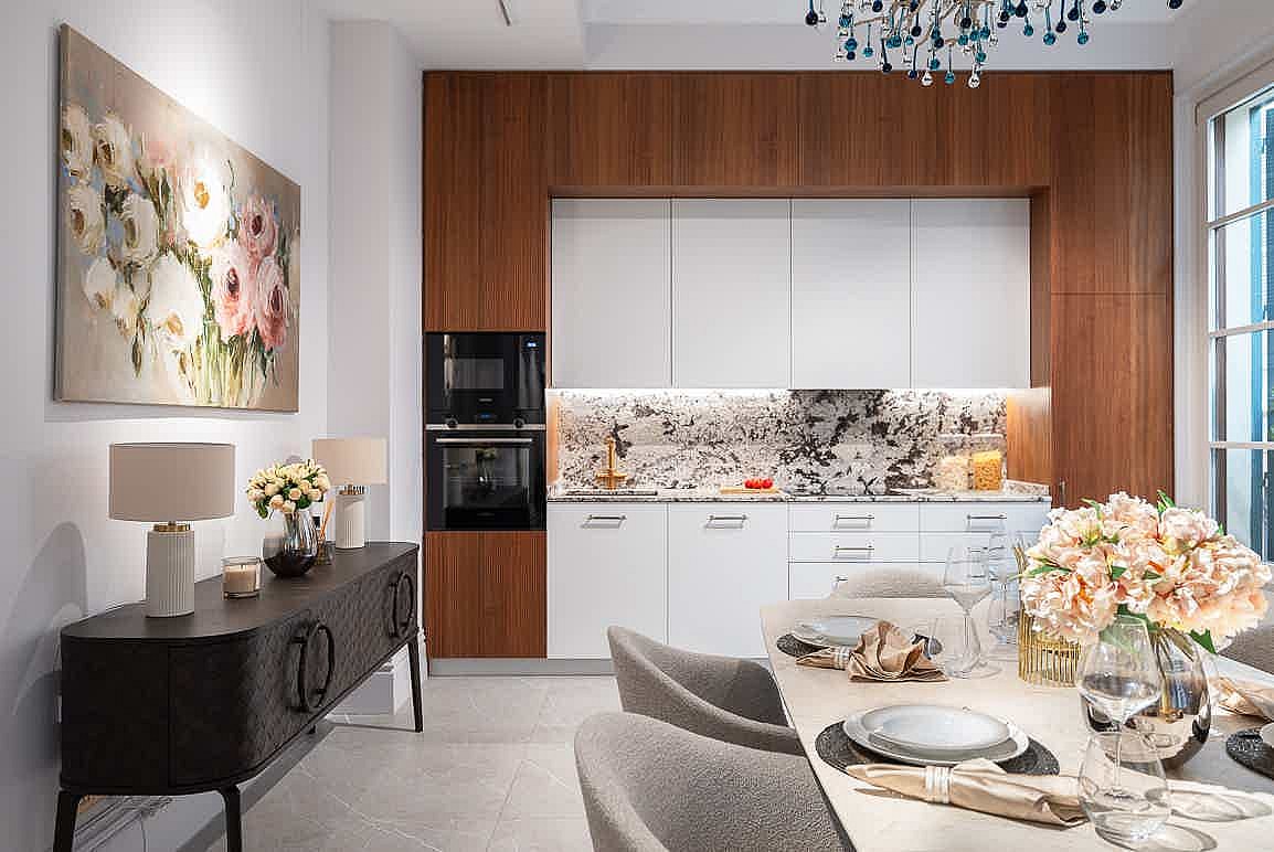 Modern kitchen with white cabinets, dark wood trim, and a patterned marble backsplash. Includes a side console and dining table.