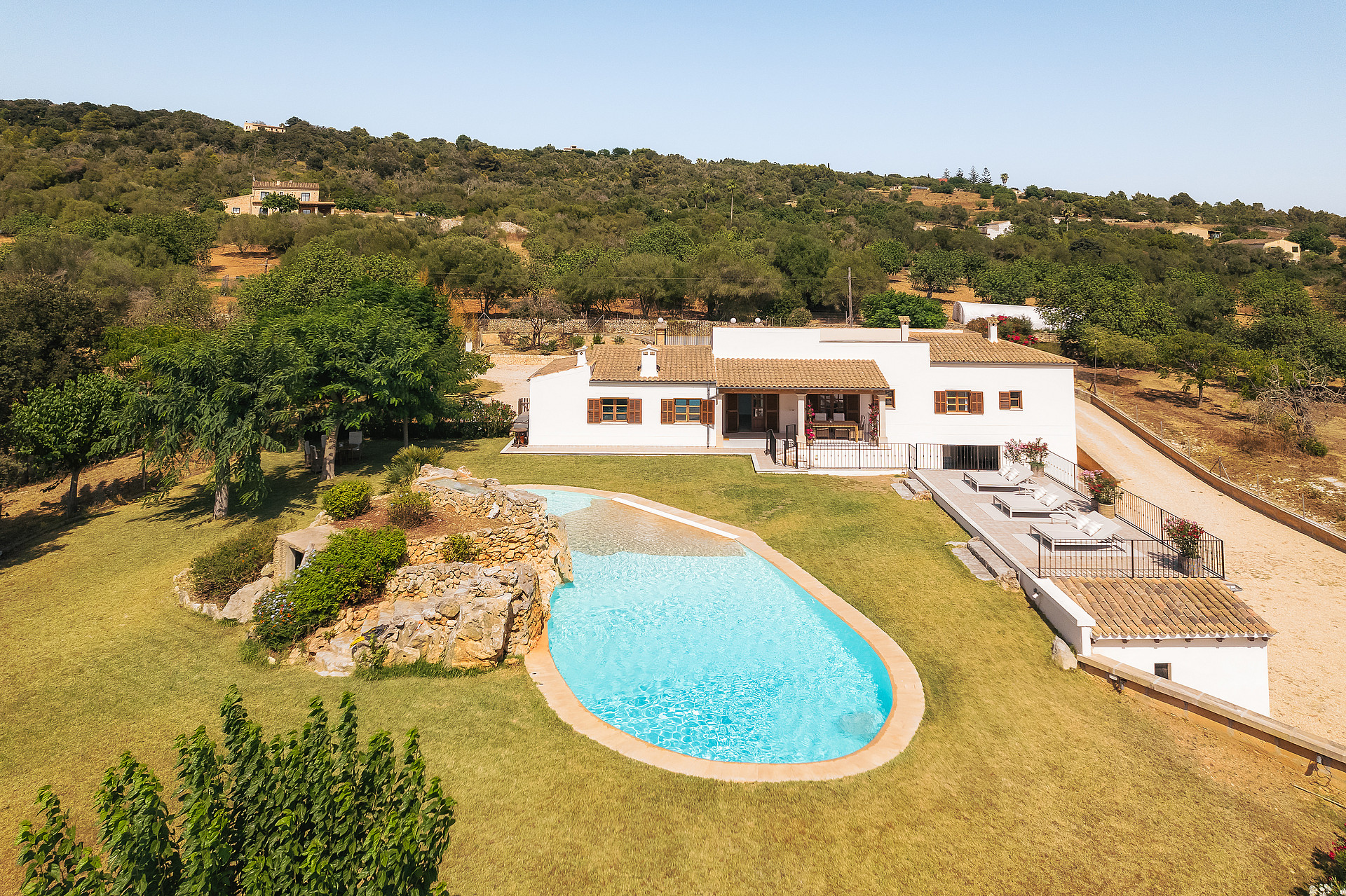 Vista aérea de finca en Manacor con piscina turquesa, jardines y colinas montañosas.