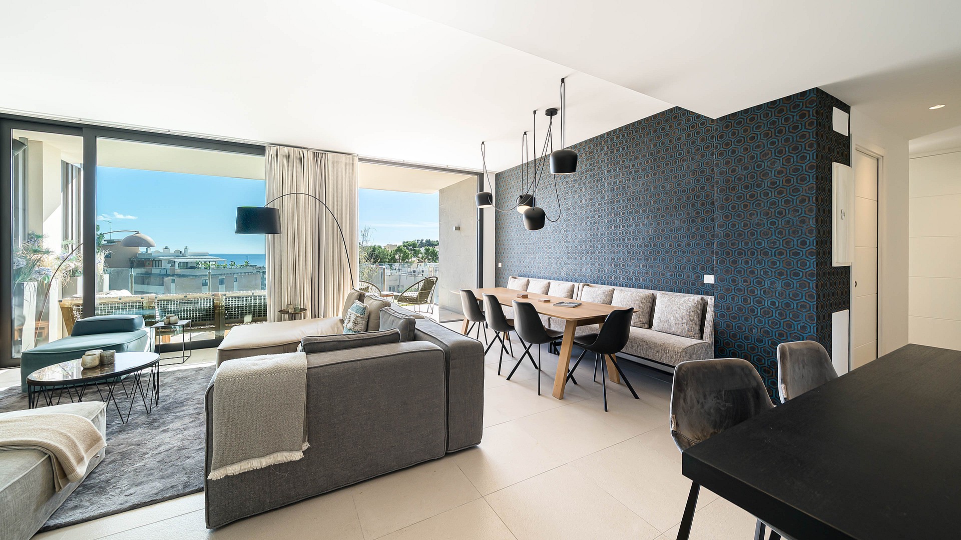Dining room with wooden table, black chairs, and upholstered bench seating set against a dark textured patterned wall.