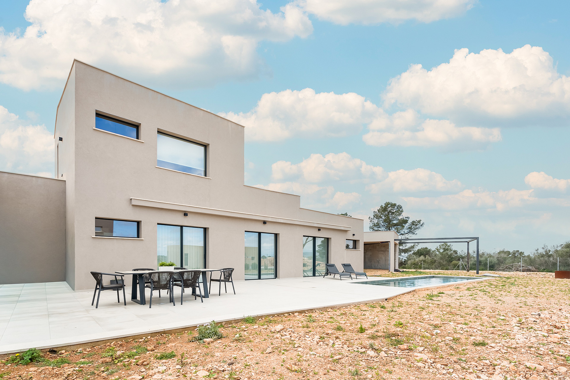 Exterior view of a contemporary villa in Son Gual featuring a concrete facade, swimming pool, and outdoor dining area.
