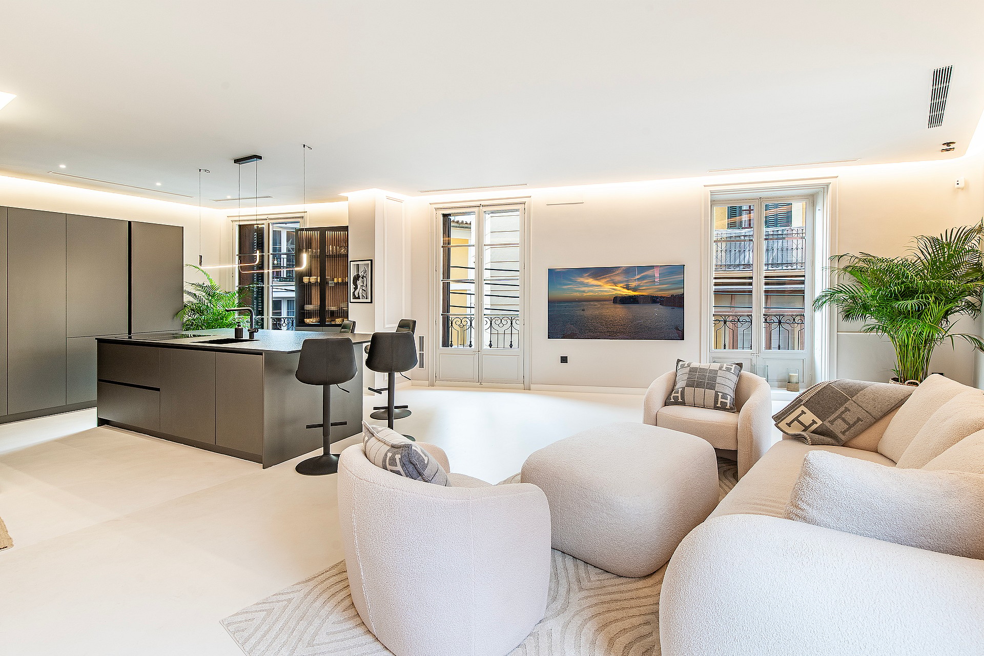 Modern open-plan living space with a dark island kitchen, textured white seating, and high ceilings in an Old Town apartment.