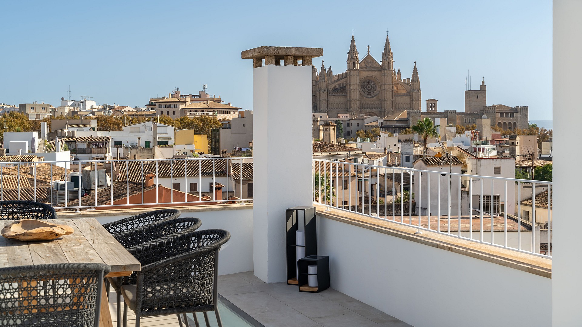 Rooftop terrace with wooden dining table and panoramic views of Palma Cathedral and the historic Old Town skyline.