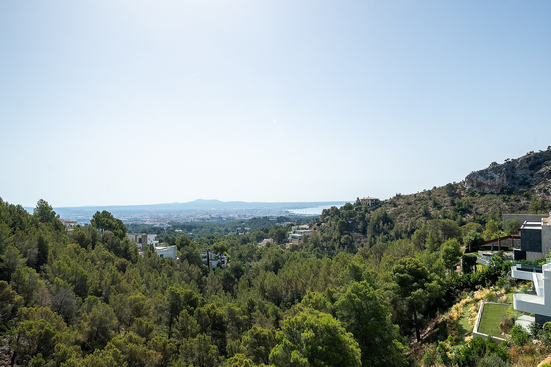 Panoramic elevated view looking over dense green pine forest towards the distant Mediterranean sea in Son Vida, Mallorca.