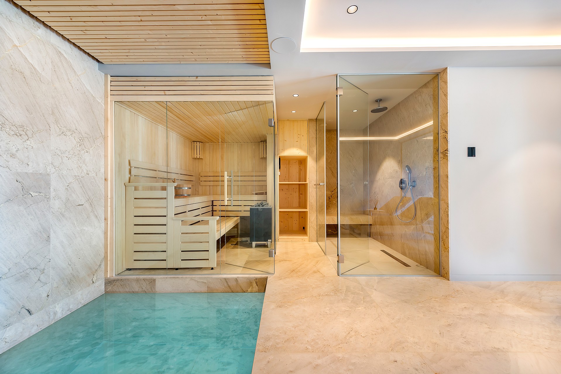 Modern home spa featuring a glass-enclosed cedar sauna beside a walk-in rainfall shower with stone flooring.