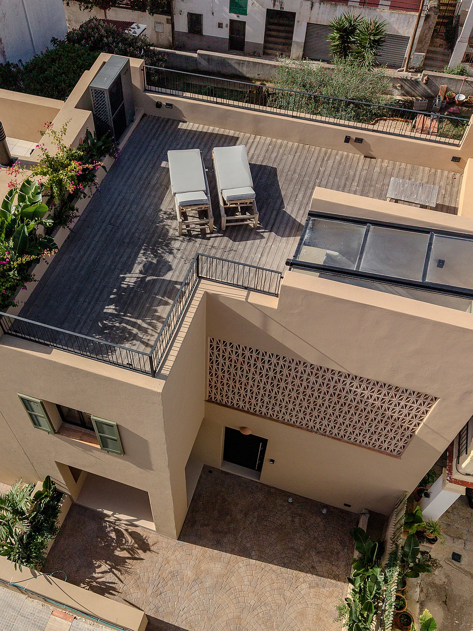 Aerial view of a townhouse rooftop terrace with wooden decking, two sun loungers, and a glass skylight section.
