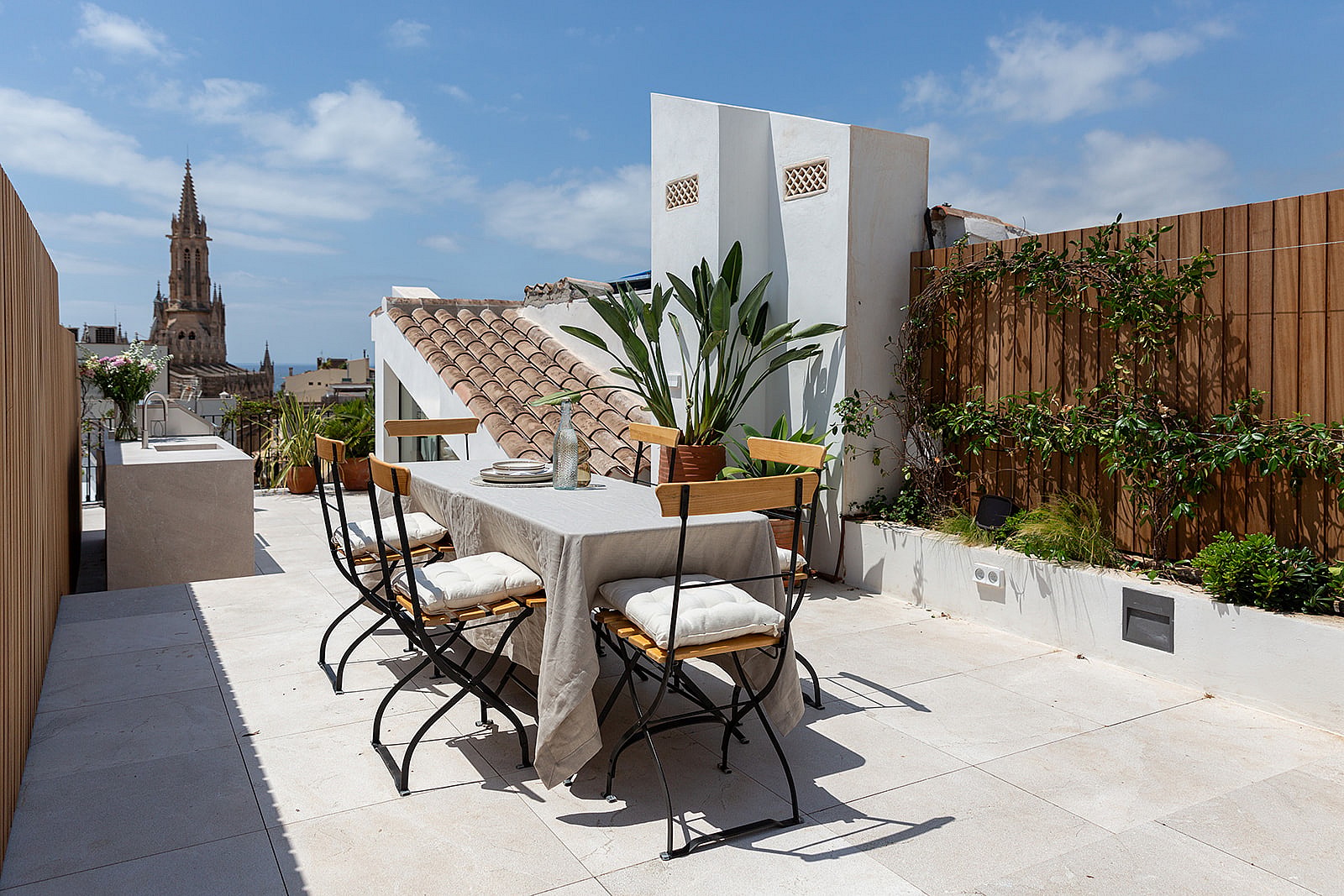 Rooftop terrace featuring an outdoor dining table, potted greenery, and views towards the Santa Eulàlia Church tower.