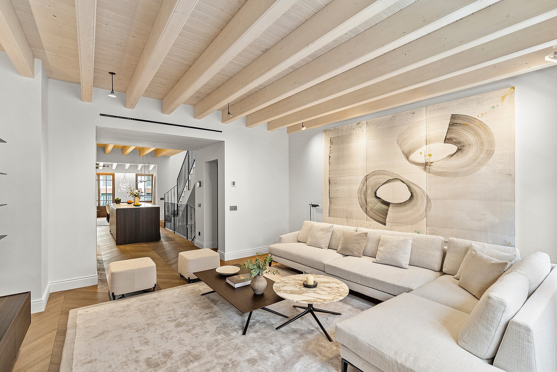 Contemporary living room featuring light wood ceiling beams, herringbone oak flooring, and neutral-toned furniture.