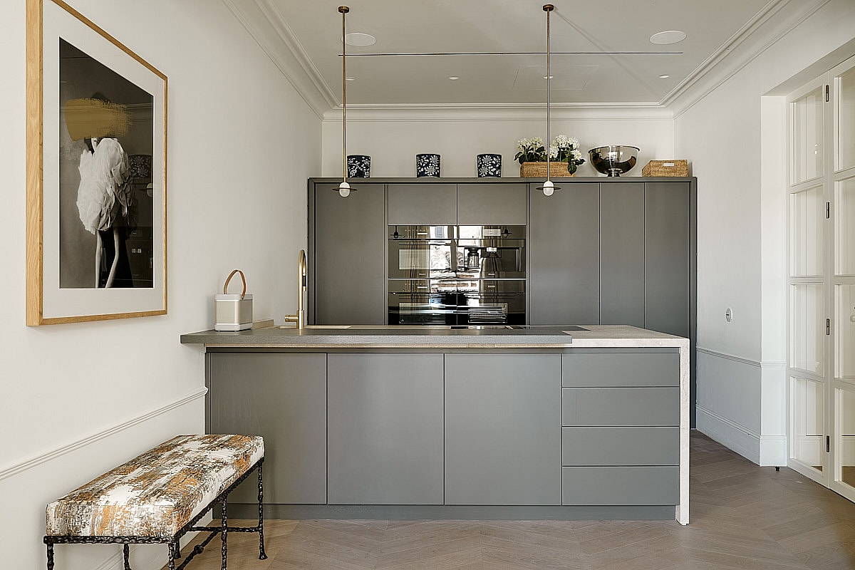 Contemporary kitchen featuring grey-toned cabinetry, professional-grade stainless steel appliances, white countertop, and brass pendant lights