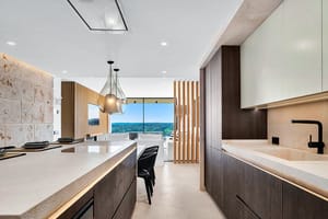 Modern kitchen with dark wood cabinetry, a stone kitchen island, and a clear view towards mountain scenery in Santa Ponsa.