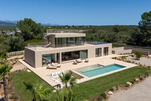 Aerial view of a modern beige villa in Son Gual featuring a rectangular swimming pool, terrace, and mountain backdrop.
