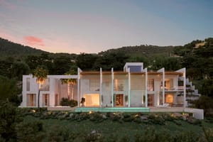 A contemporary two-story white villa featuring vertical privacy louvers and a linear swimming pool at sunset.